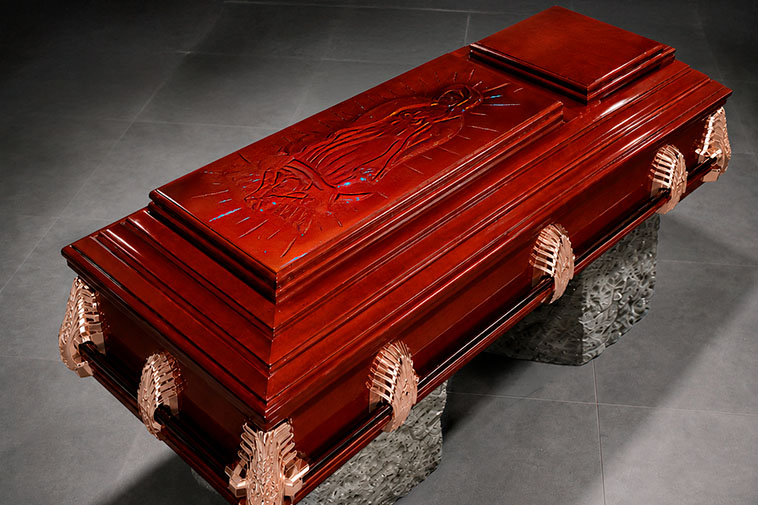 Ataúd de madera de lujo con asas de metal; lleva grabado en la cubierta una figura religiosa. Es usado para homenajes de despedida en la Funeraria Valparaíso, ubicada en Toluca, Estado de México.
