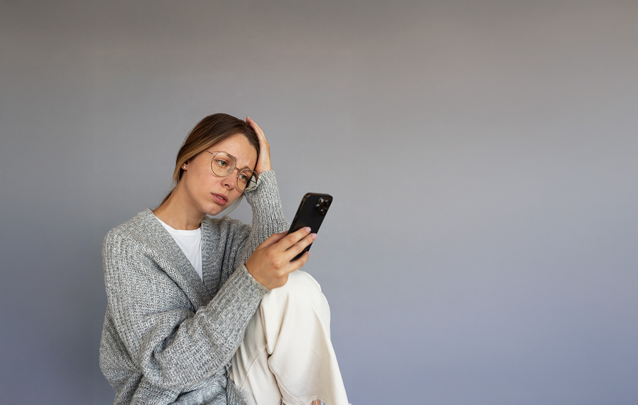 Mujer joven mirando su celular de con una mirada de angustia.